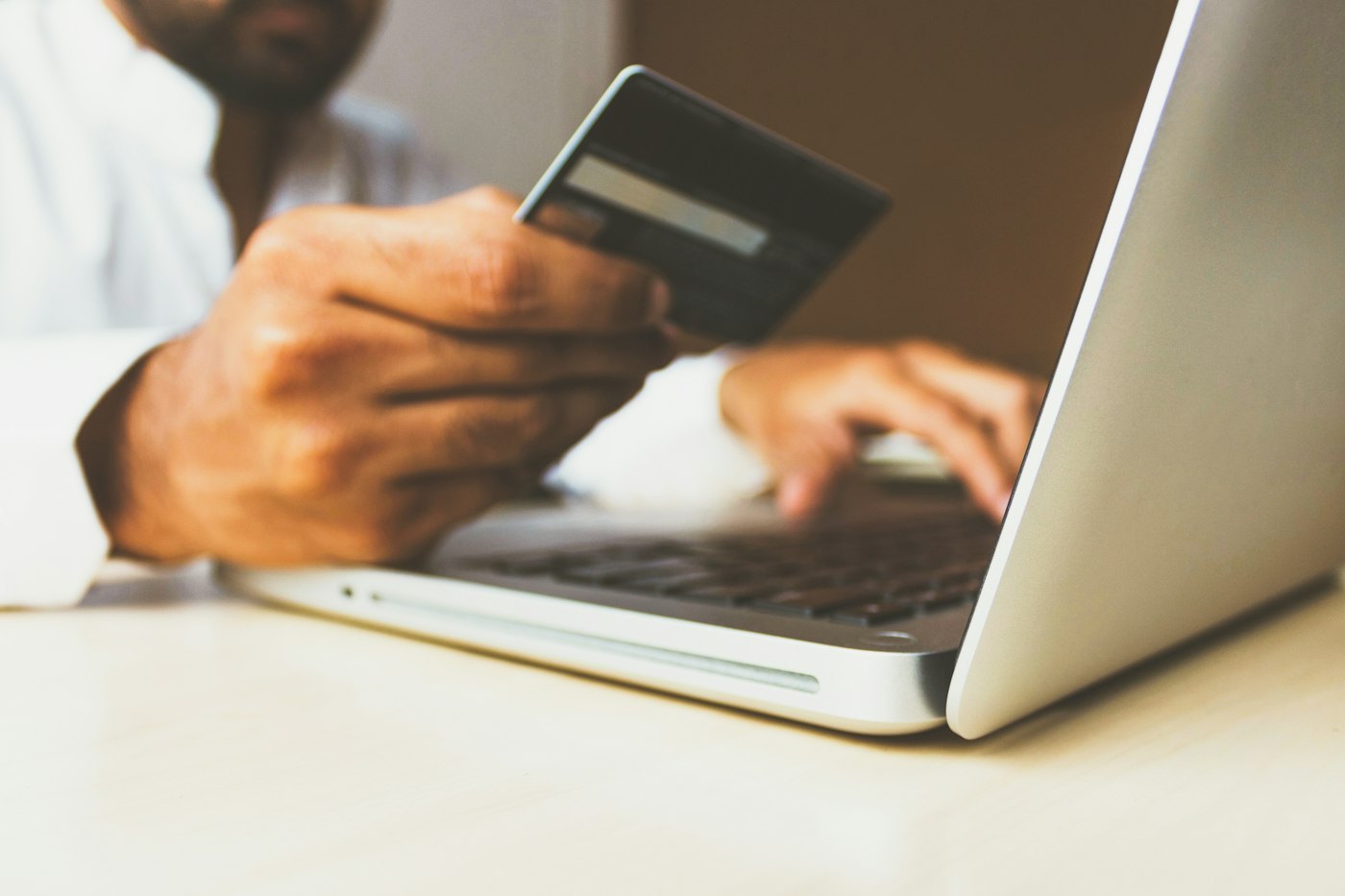 Pessoa com cartão de crédito no notebook, risco de compra em site falso