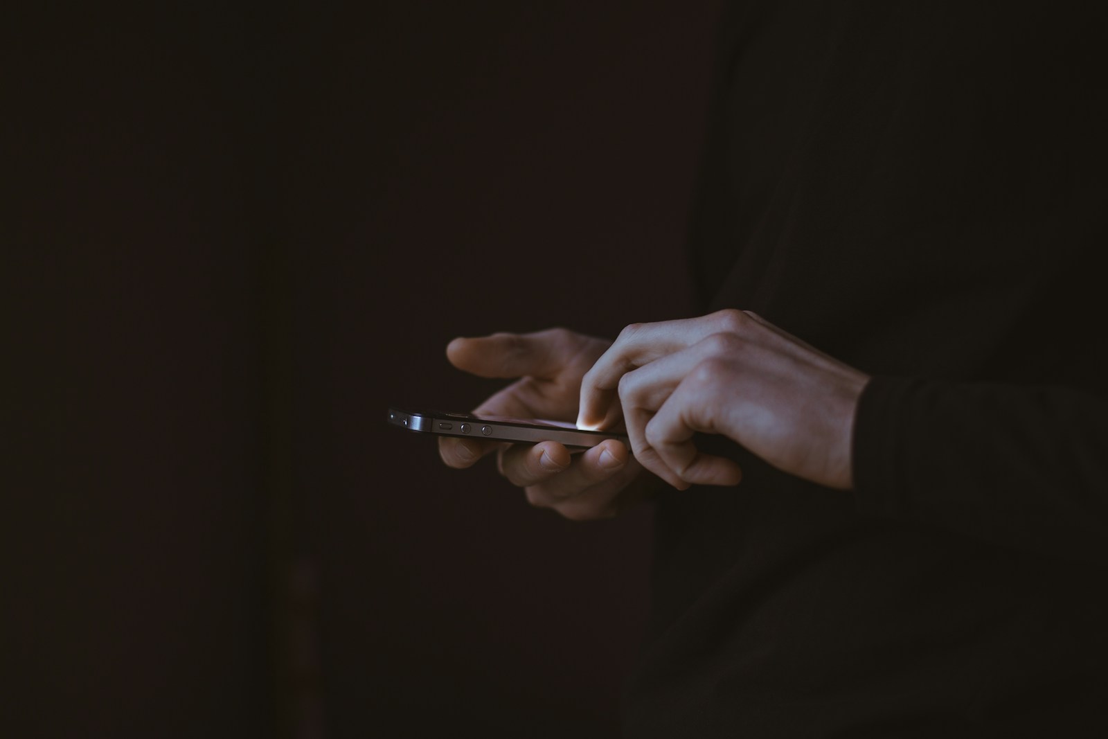 Conta aberta em seu nome por golpista: pessoa segurando celular no escuro