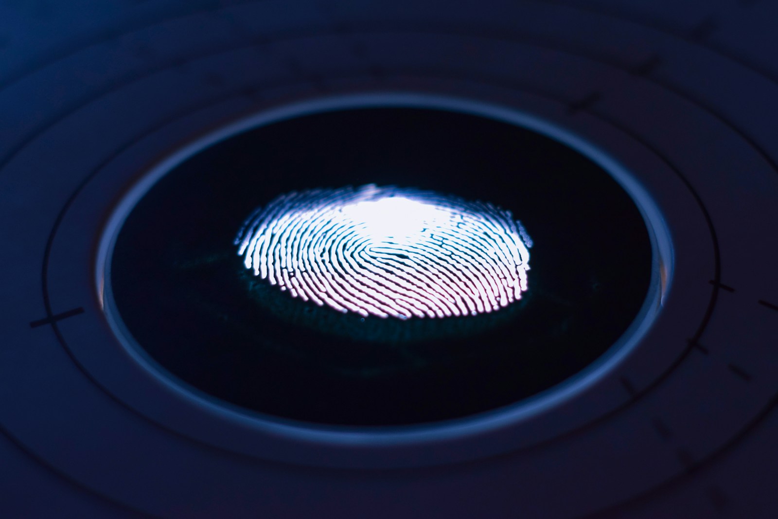 Fraude de identidade no onboarding: leitor biométrico de impressão digital em fundo escuro
