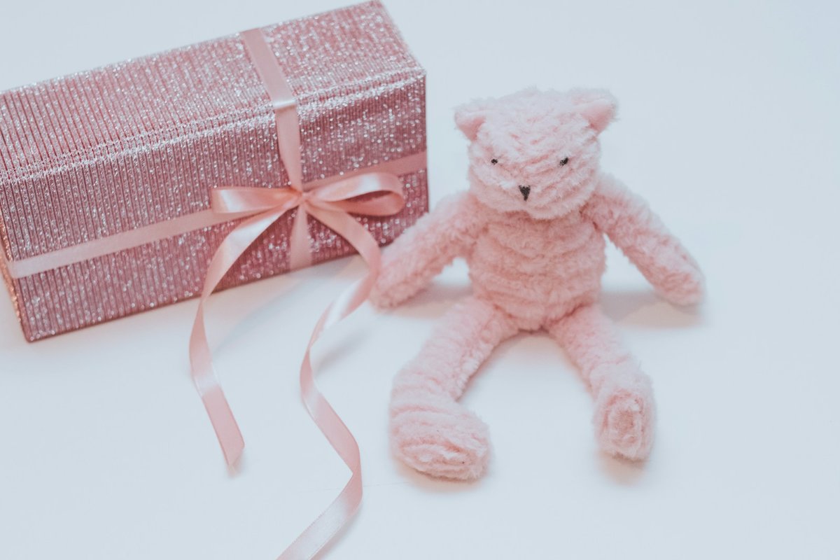 Urso de pelúcia ao lado de caixa de presente, ilustrando o golpe no Dia das Crianças em lojas falsas