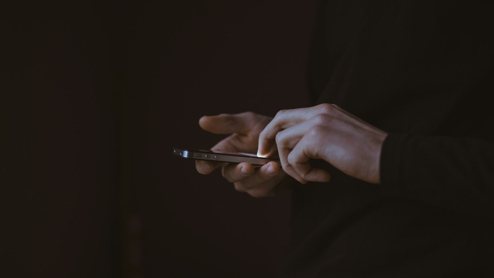 Golpe do falso advogado: pessoa lê mensagem no celular em ambiente escuro