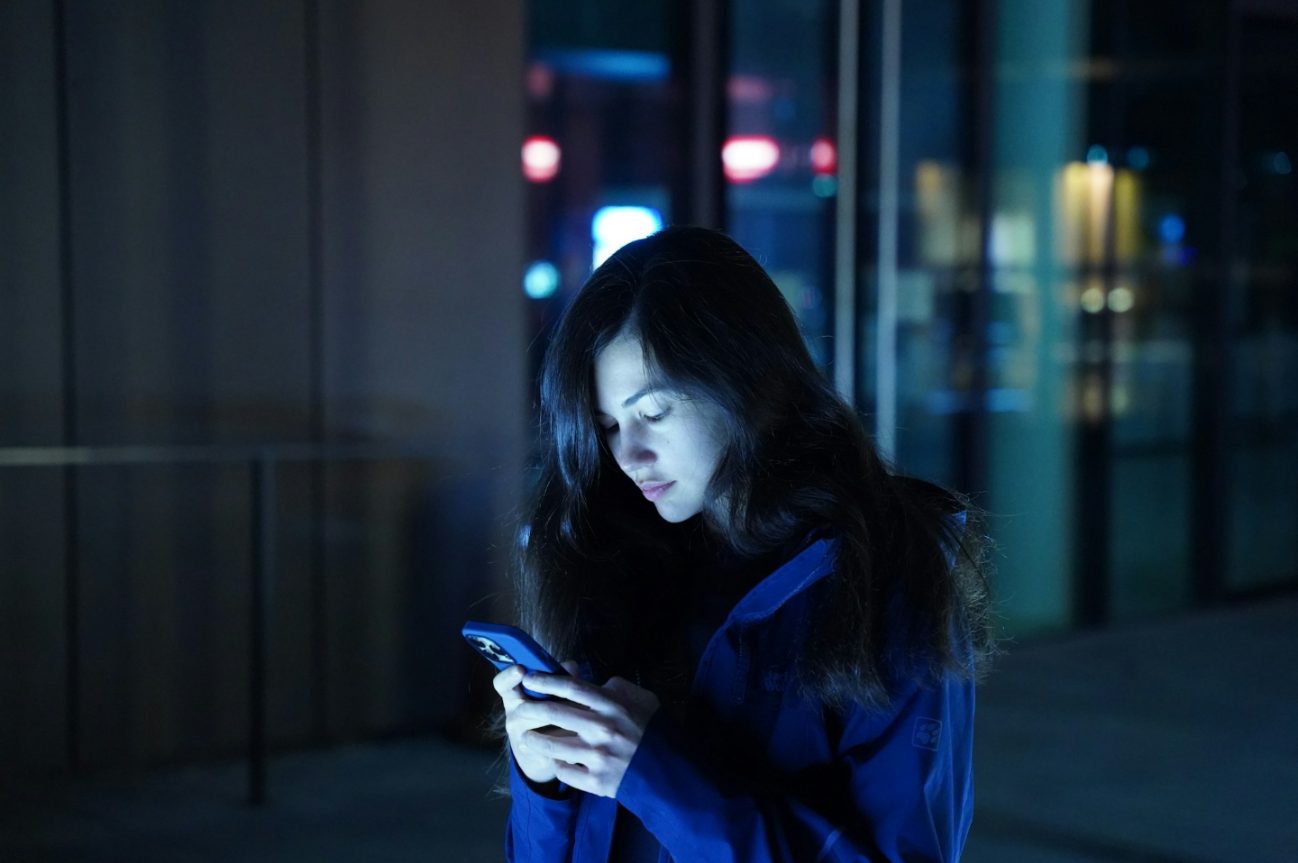 Mulher lê mensagem no celular à noite