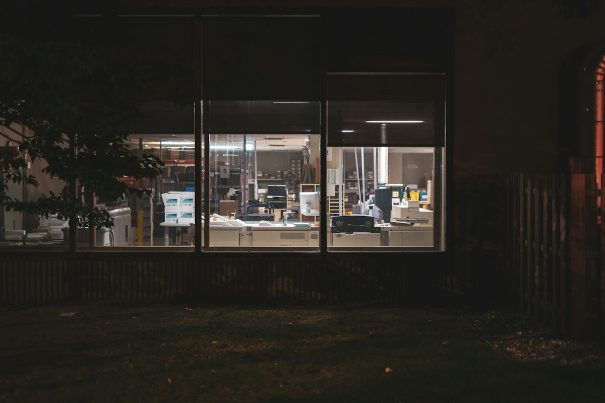 Fraude organizada contra empresas: prédio comercial com escritório iluminado à noite